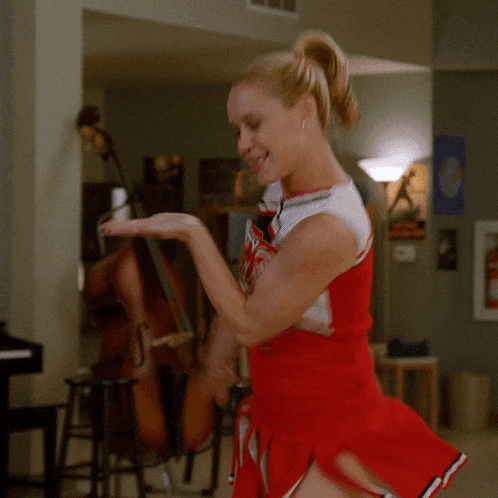 a cheerleader in a red dress is dancing in front of a double bass