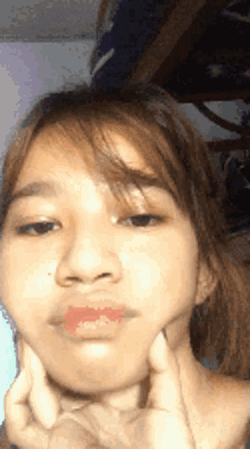 a close up of a girl 's face with her hands on her face