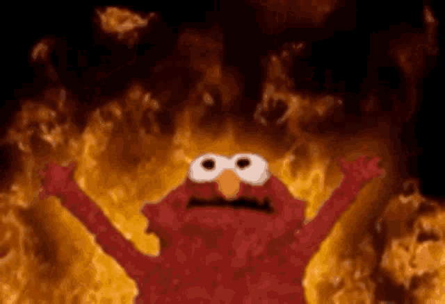 elmo from sesame street is standing in front of a fireball .