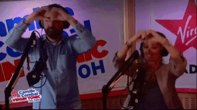 a man and a woman are making a heart shape with their hands in front of a sign that says virgin