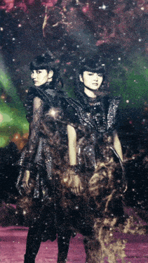 a couple of girls standing next to each other in front of a colorful background