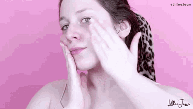 a woman is applying a cream to her face with her hands .