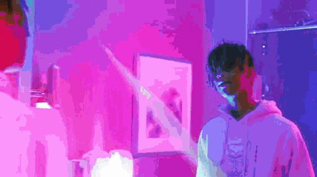 a man in a purple hoodie is standing in front of a mirror