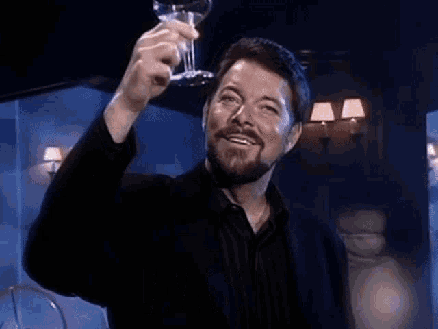 a man with a beard is holding a glass of wine and the word cheers is on the bottom