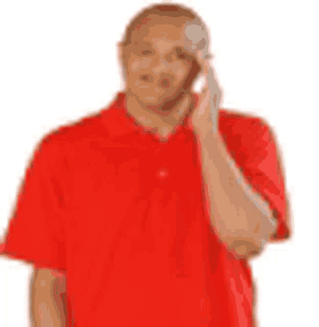 a man in a red shirt is talking on a cell phone .