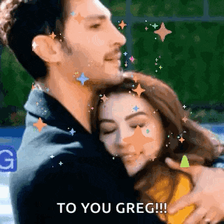 a man is hugging a woman with the words `` to you greg '' written on the screen .