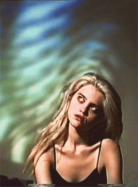 a woman in a black tank top stands in front of a green and blue background