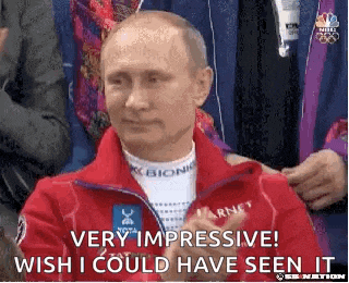 a man in a red jacket is sitting in front of a crowd .