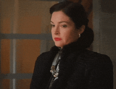 a woman wearing a black jacket and earrings looks to the side .