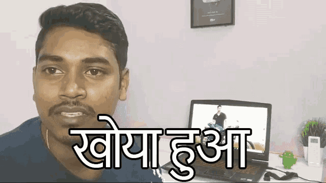 a man sitting in front of a laptop with a sign that says ' swaya ' on it