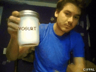 a man in a blue shirt holds a jar of yogurt in his hand
