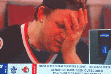a man covering his face while watching the maple leafs defeat senators 3-2