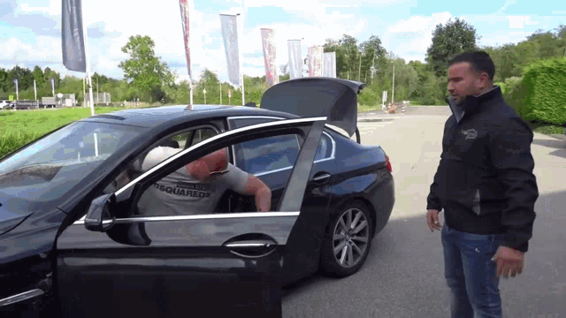 a man in a dsquared2 shirt sits in a black car
