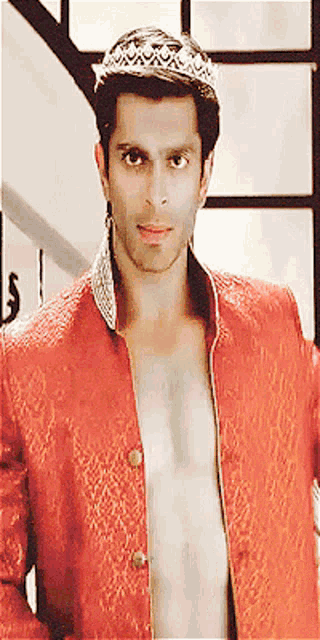 a shirtless man wearing a red jacket and a crown