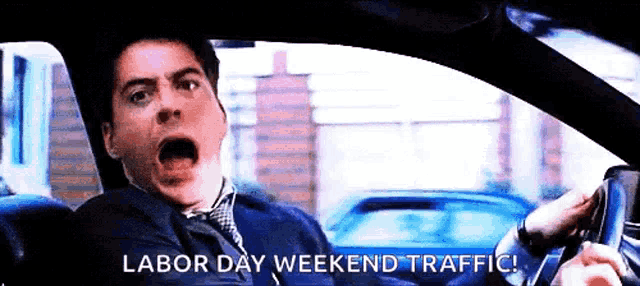 a man is driving a car with the words labor day weekend traffic written on the screen