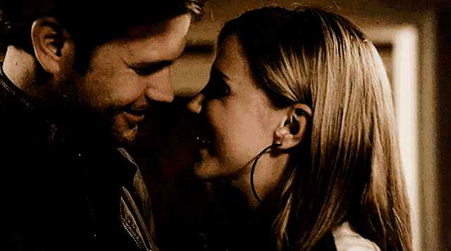 a man and a woman are looking at each other and smiling