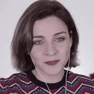a woman wearing headphones and a colorful sweater is making a face .