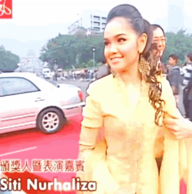 a woman standing on a red carpet with the name siti nurhaliza on the bottom right