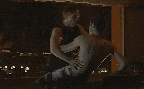 a man and a woman are having sex in a room with a view of the city at night .