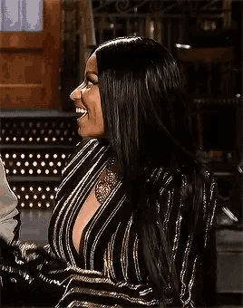 a woman wearing a striped jacket and a gold necklace is laughing