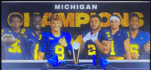 a group of michigan football players standing next to a trophy