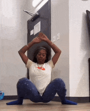 a woman squatting on the floor with her legs crossed and a nike shirt on