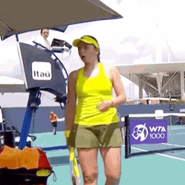 a woman holding a tennis racquet on a tennis court sponsored by itaú