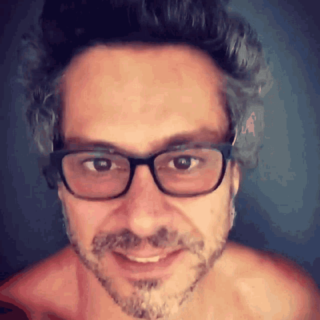 a man with glasses and a beard is smiling for the camera