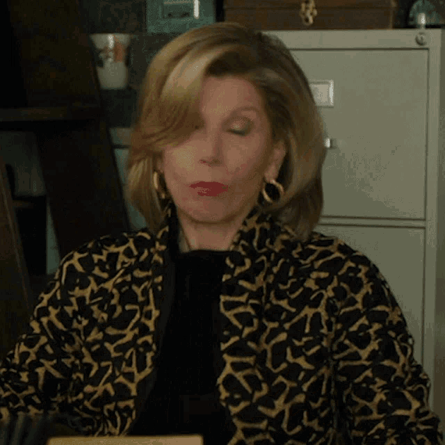a woman wearing a leopard print jacket and gold earrings