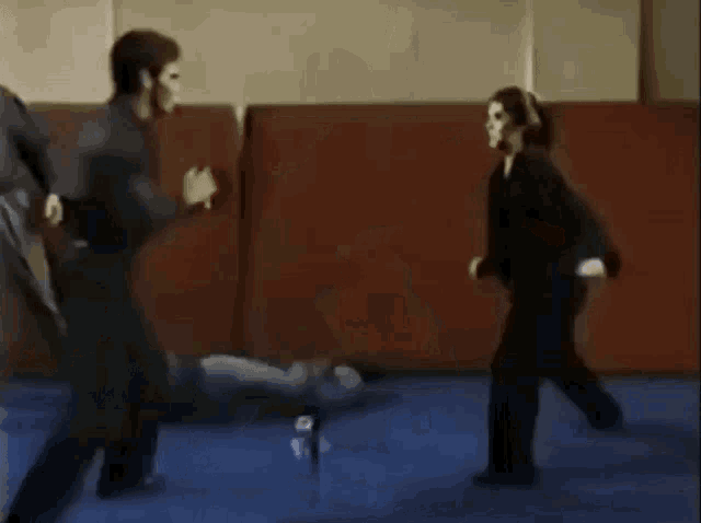 a man and a woman are practicing martial arts on a mat in a gym .