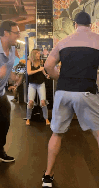 a man and a woman are dancing in a room with a painting on the wall behind them