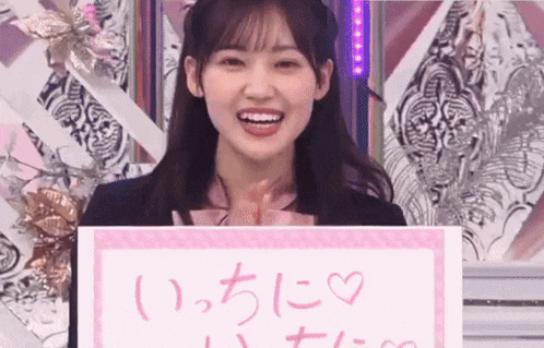a girl is holding a sign that says `` i love you '' in a foreign language .