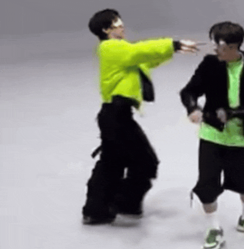a man in a green jacket is dancing with another man in a black jacket .