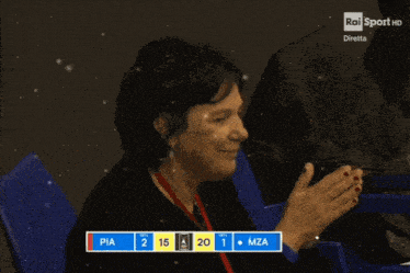 a woman clapping in front of a scoreboard that says pia 2 15 mza 1