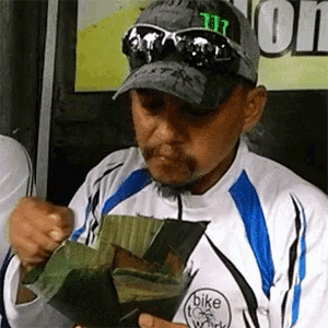 a man wearing a hat that says monster on it is eating a piece of food