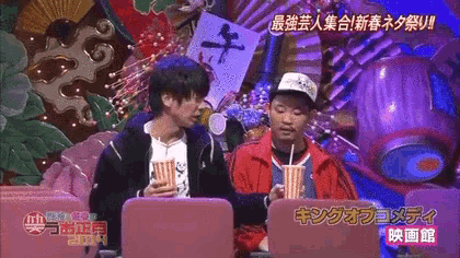 two men are sitting in front of a screen that says king on it