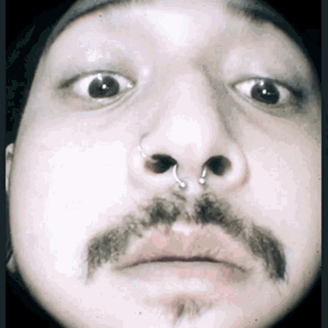 a man with a nose ring and a mustache makes a funny face