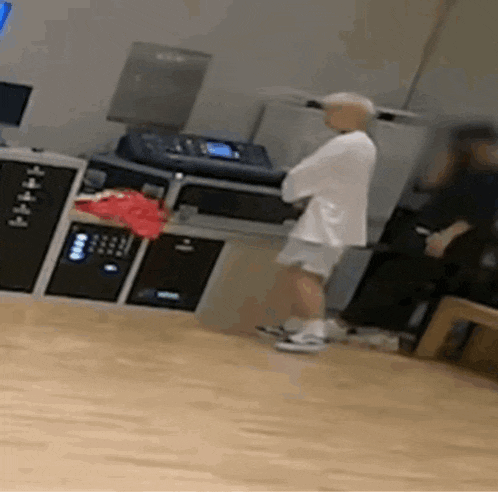 a man in a white shirt and shorts is standing on a wooden floor .