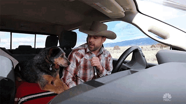 a man in a cowboy hat is singing into a microphone in a car