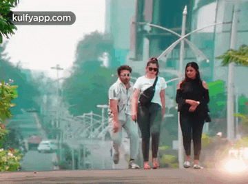 a man and two women are walking down a street .
