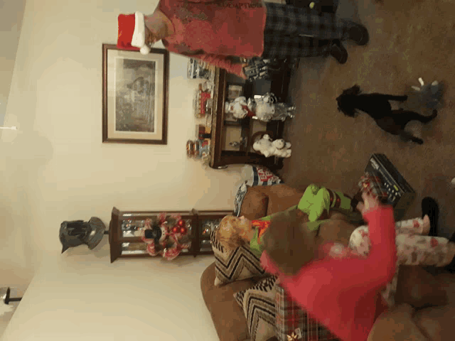 a man in a santa hat stands in a living room with two children