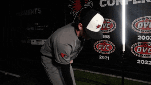 a baseball player is standing in front of a banner that says ovc