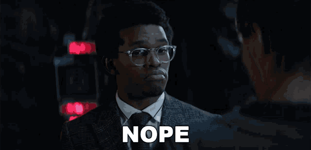 a man wearing glasses and a suit has the word nope on his face
