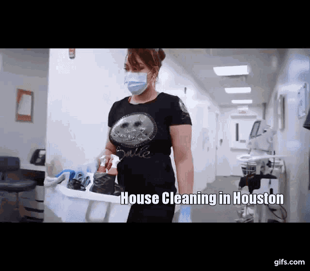 a woman wearing a mask is carrying a bucket full of cleaning supplies in a hospital hallway