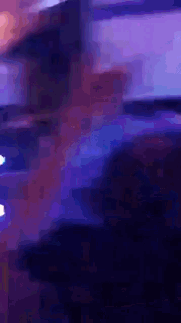 a blurry picture of a person standing in a dark room with purple lights