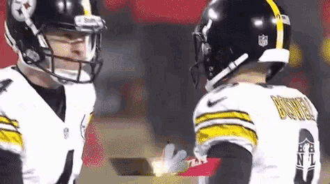 a couple of football players are standing next to each other on a field .