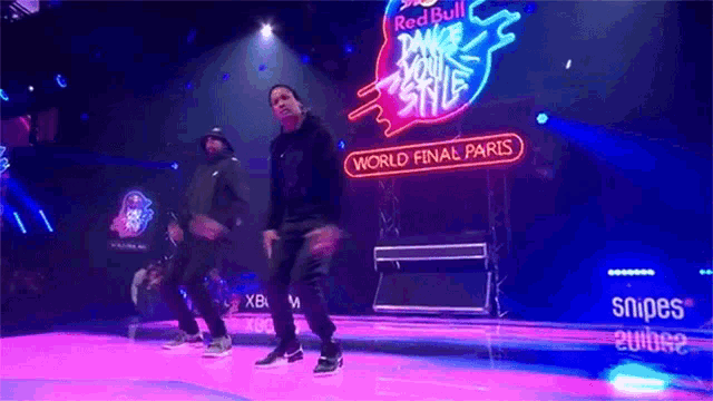 two men are dancing on a stage in front of a sign that says world final paris