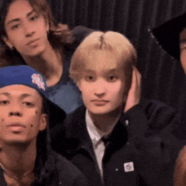 a group of young men are posing for a picture and one of them is wearing a blue hat