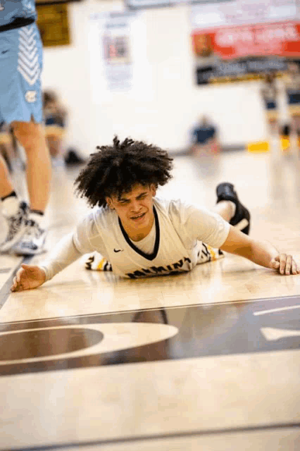 a basketball player laying on the floor wearing a shirt that says ' nebraska ' on it