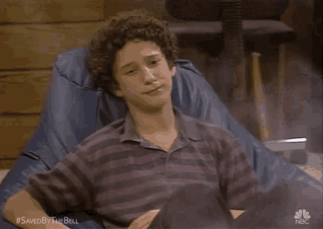 a young man with curly hair is sitting in a bean bag chair .